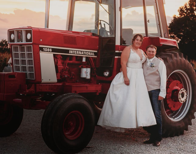 Raelynn and Sam standing by Farmall tractor