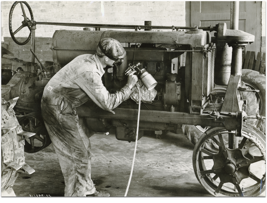 Black and white image of a man painting a 1931 Farmall F series