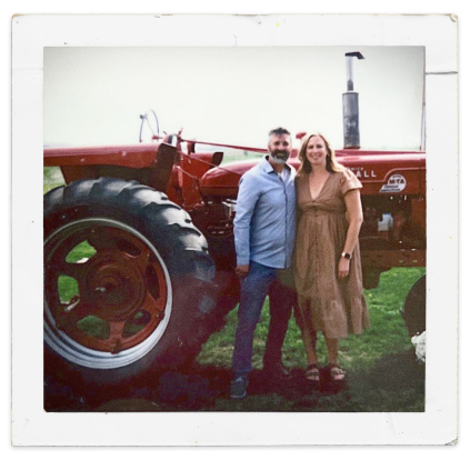 Man and woman standing in front of historic Farmall