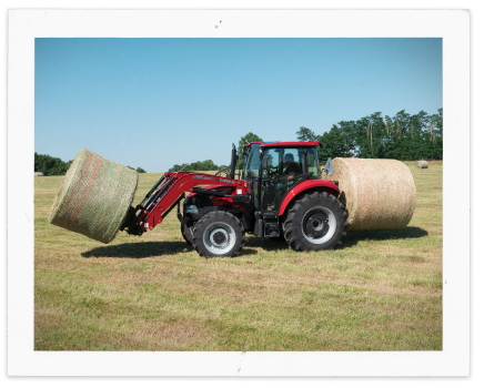 Farmall tractor lifting hay bale